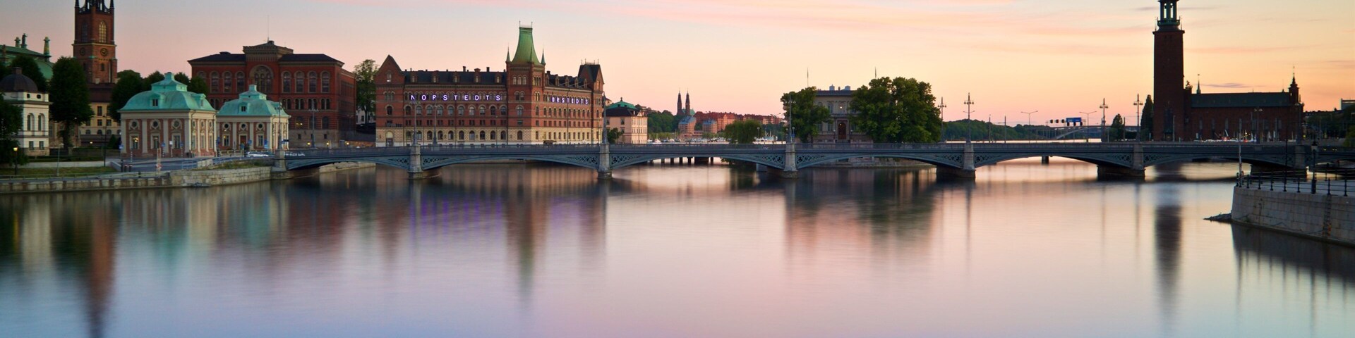 Un río con un puente, edificios históricos y una torre que se refleja en el agua.