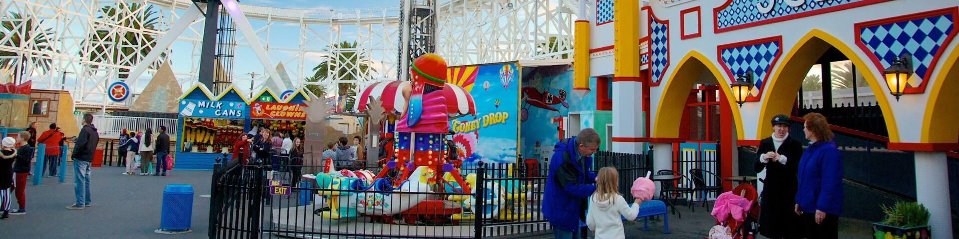 A colorful amusement park with a Ferris wheel, a cotton candy ride, and a building with 'SCENIC' written on it.