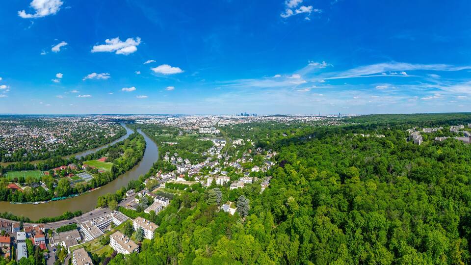 A river winding through a city surrounded by dense green forests.