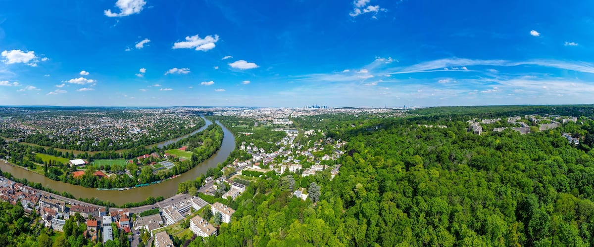 A river winding through a city surrounded by dense green forests.