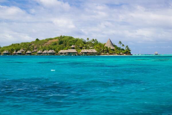 A tropical island with overwater bungalows and clear turquoise waters.