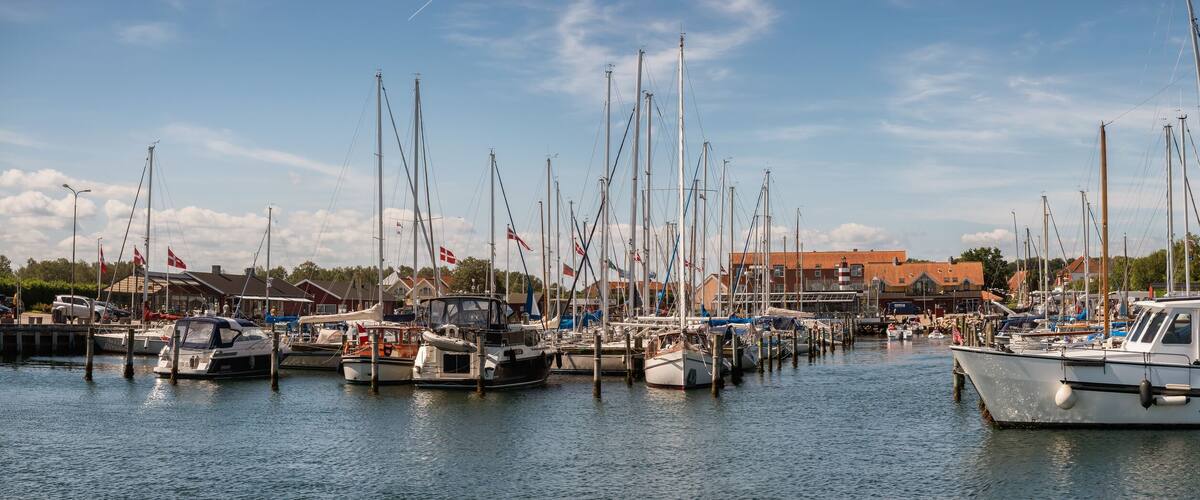 A marina with various boats docked, surrounded by buildings and a clear sky.