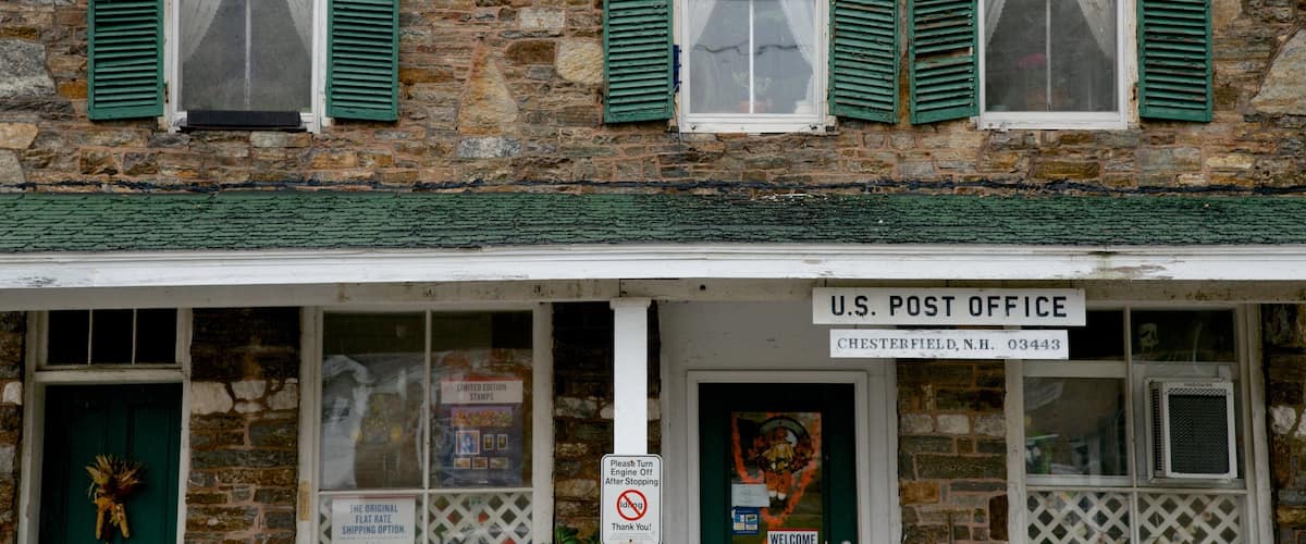 Una oficina de correos estadounidense en Chesterfield, Nuevo Hampshire, con muros de piedra y contraventanas verdes.