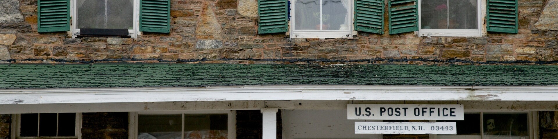 Una oficina de correos estadounidense en Chesterfield, Nuevo Hampshire, con muros de piedra y contraventanas verdes.