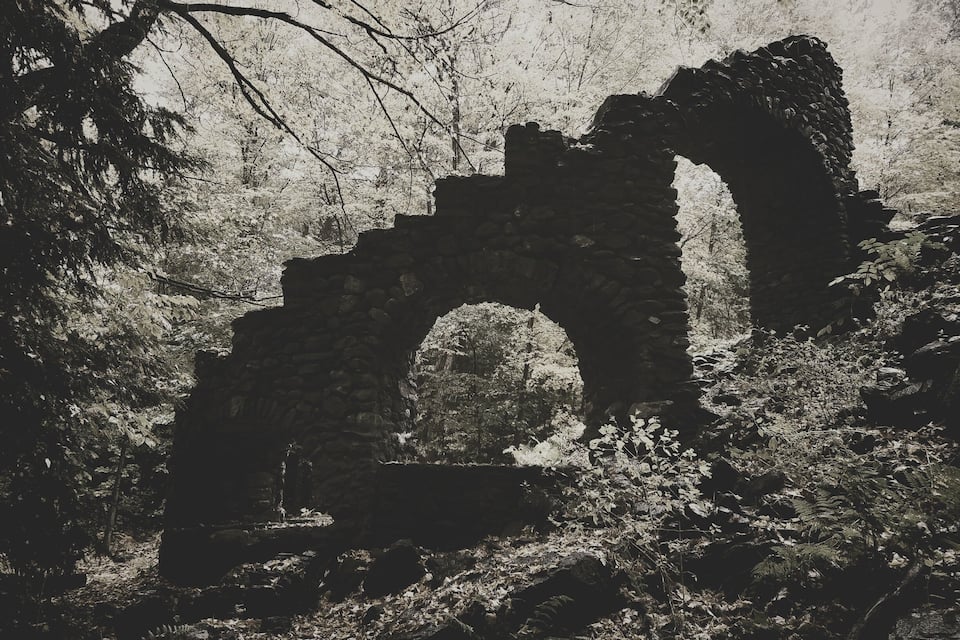 An ancient stone archway surrounded by dense forest.