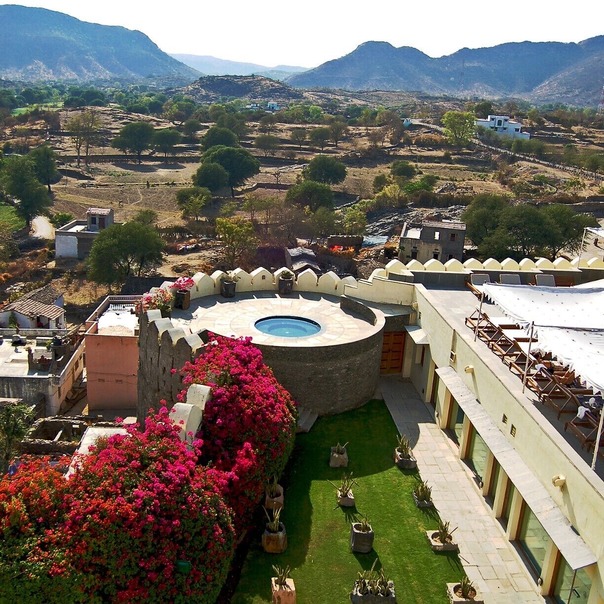 A courtyard with a pool, surrounded by buildings and mountains.