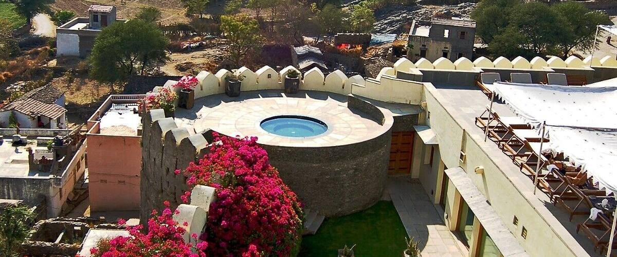 A courtyard with a pool, surrounded by buildings and mountains.