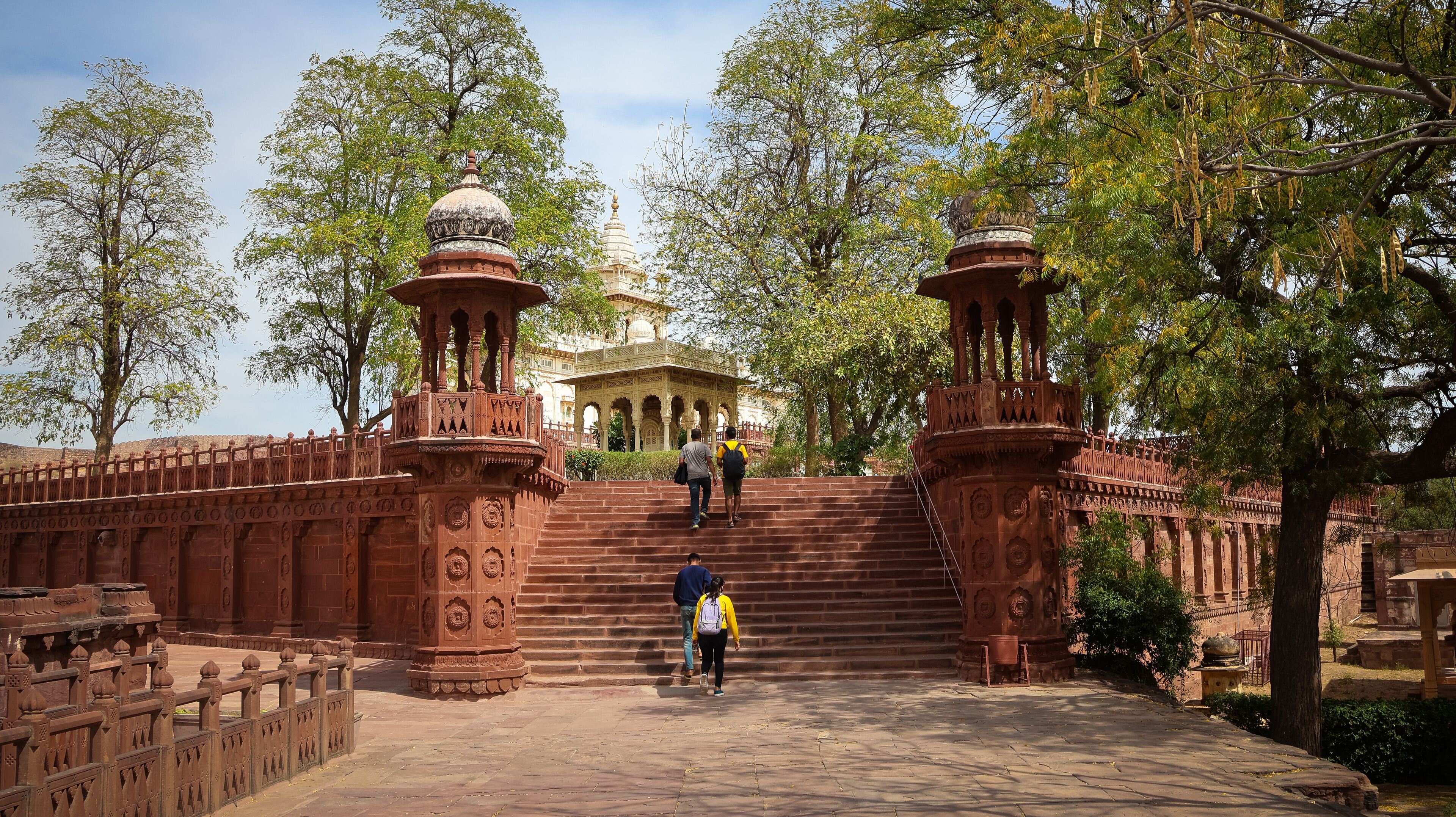 A historic site with a grand staircase leading to a temple, surrounded by lush trees and intricate architecture.