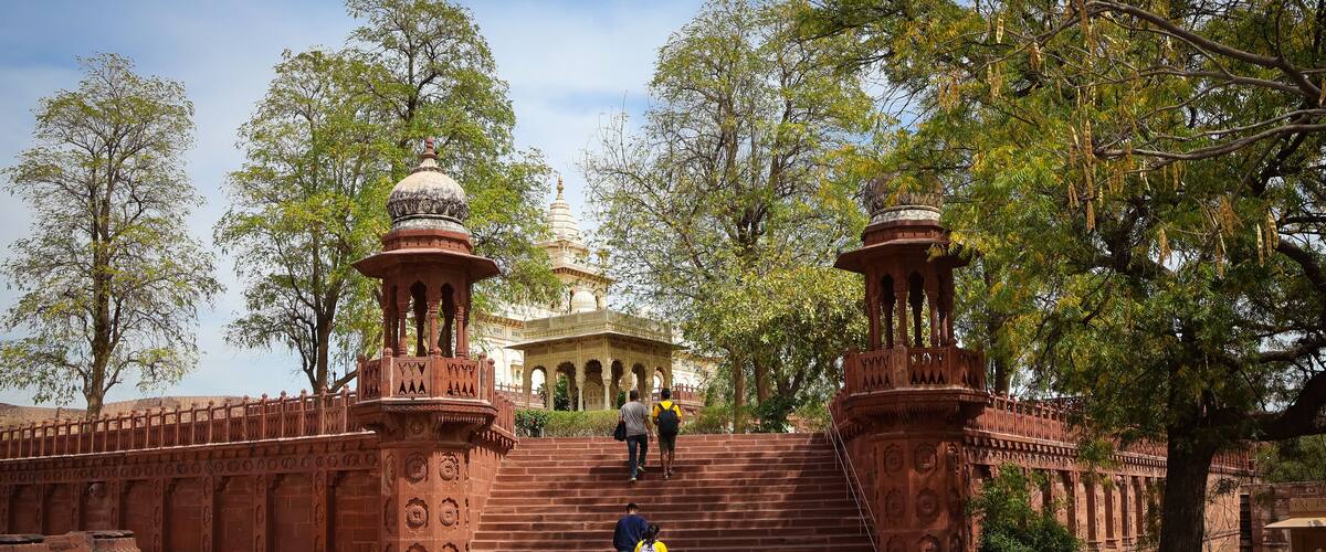 A historic site with a grand staircase leading to a temple, surrounded by lush trees and intricate architecture.