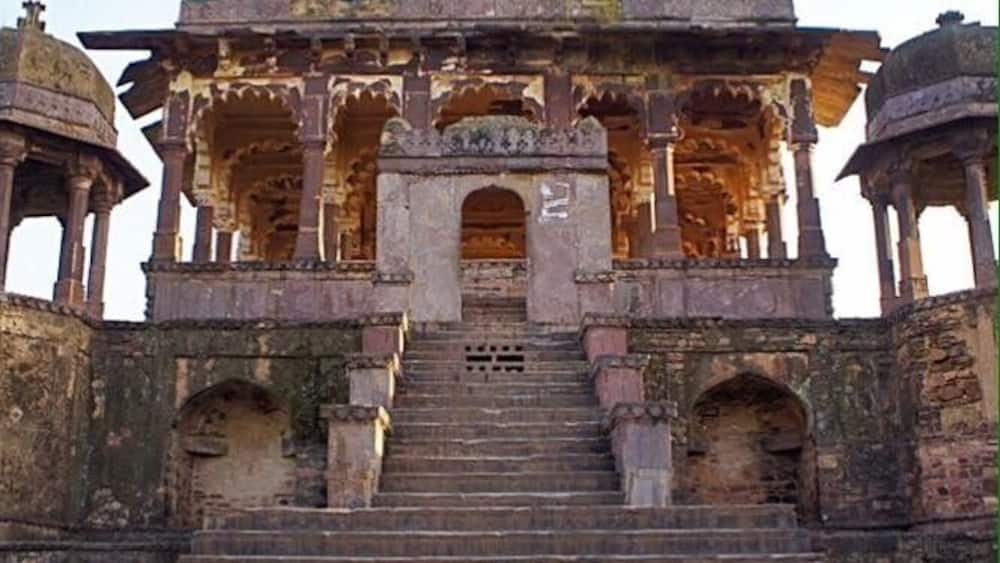 A historical building with multiple domes, a central archway, and a staircase leading up to it.
