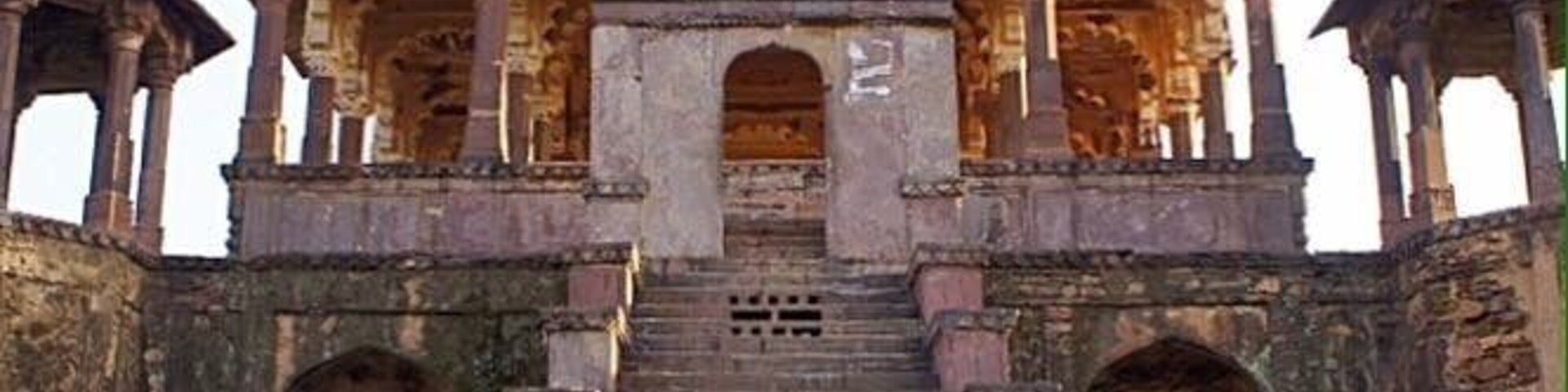 Un edificio histórico con múltiples cúpulas, un arco central y una escalera que conduce a él.