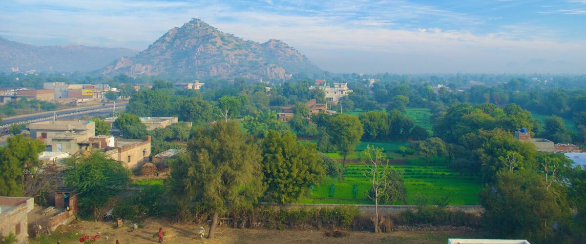 A mountainous landscape with a village in the foreground and a river in the distance.