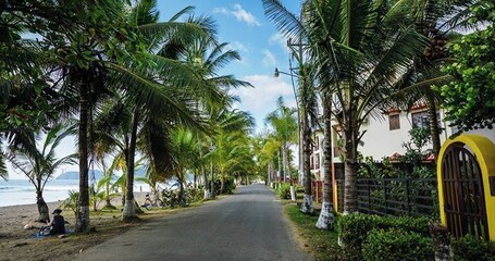 Eine Küstenstraße gesäumt von Palmen und Häusern, die zum Strand führt.