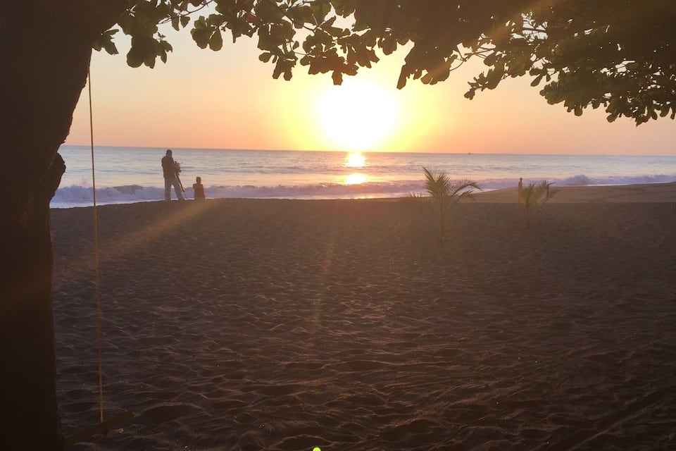 A beach at sunset with people walking along the shore.
