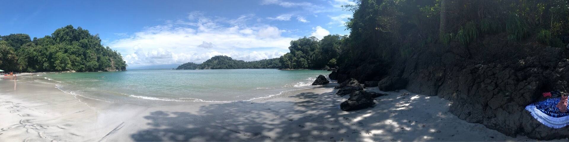 A beach with clear turquoise water, white sand, and rocky cliffs.