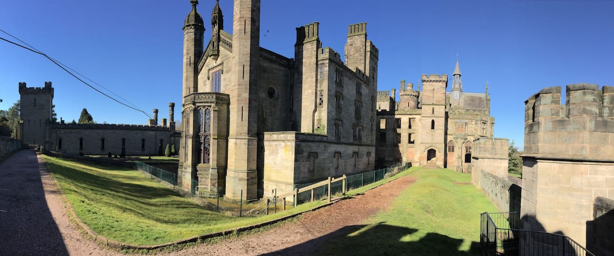 A historic castle with tall towers, a large courtyard, and a stone wall.