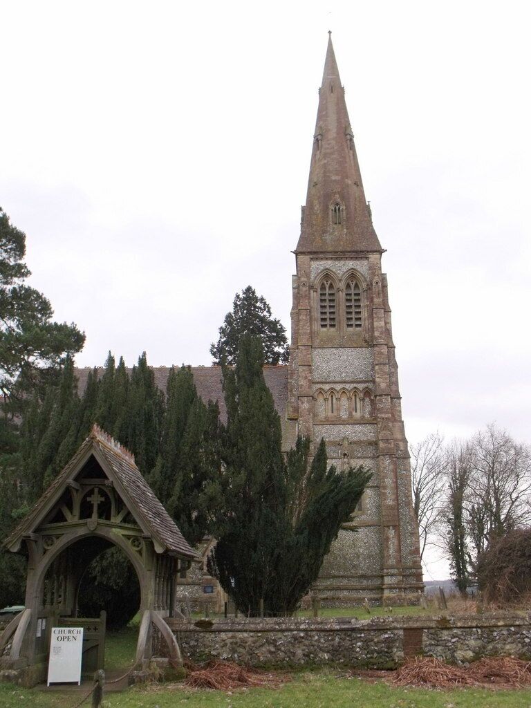 A church with a tall spire and a small entrance structure.
