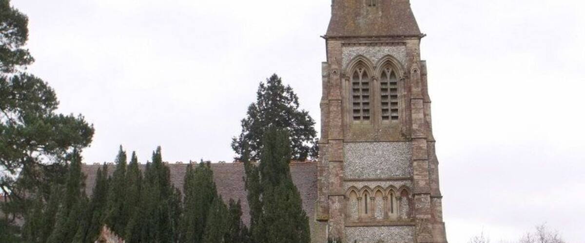 A church with a tall spire and a small entrance structure.