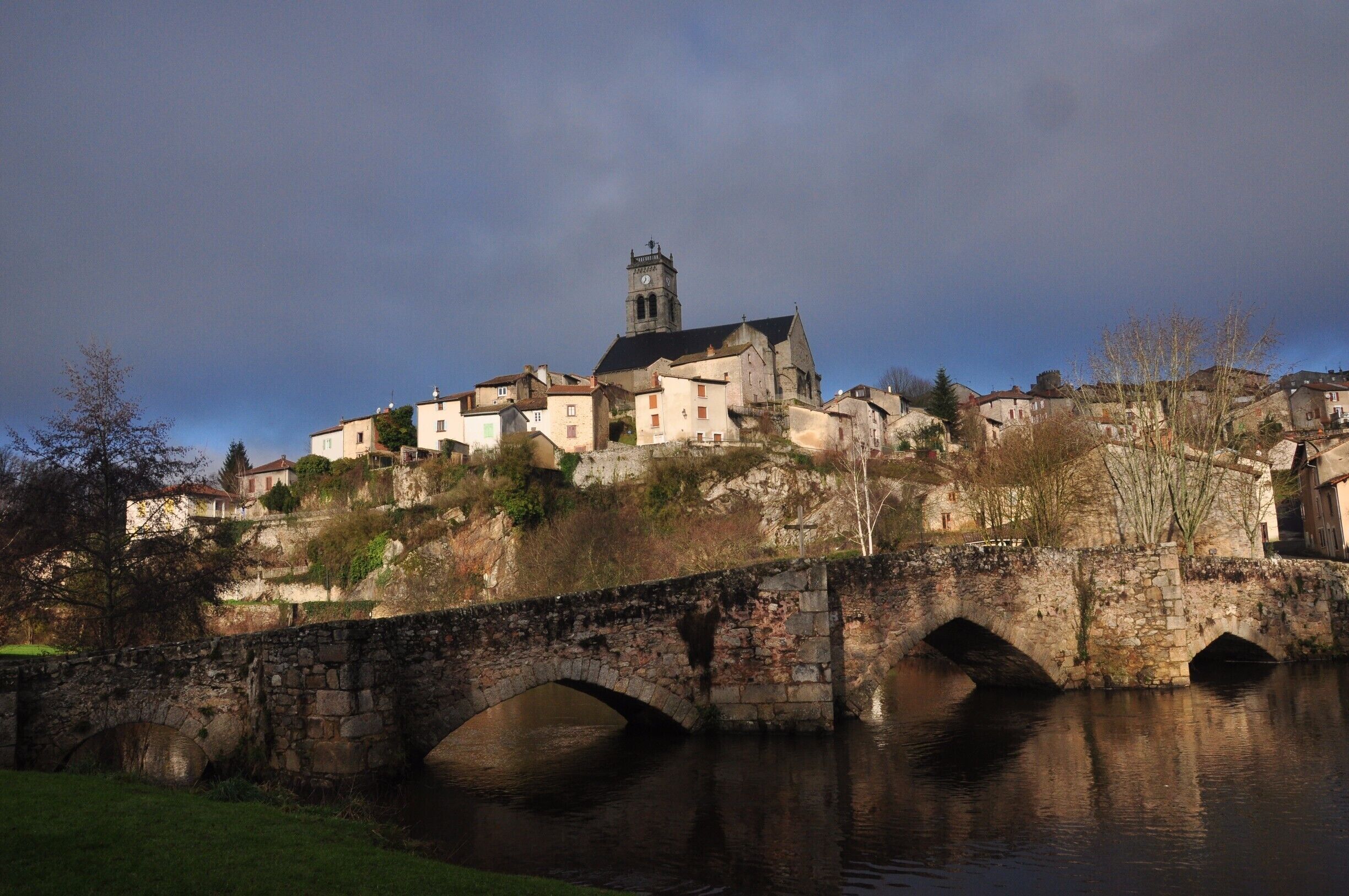 A historic town with a prominent church and a stone bridge over a river.
