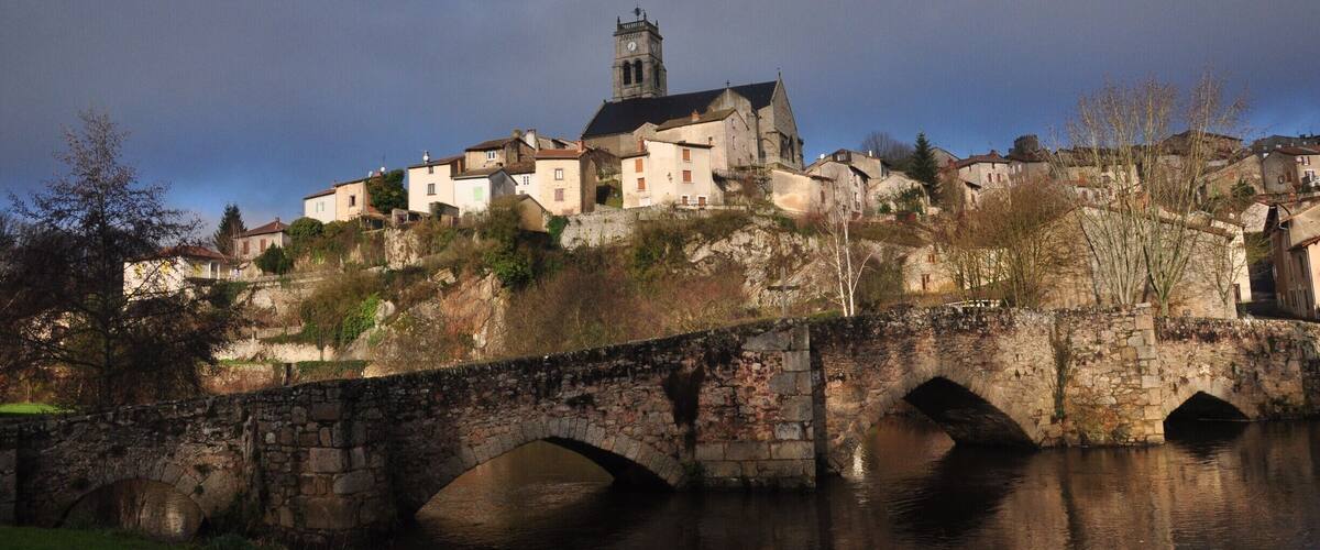 A historic town with a prominent church and a stone bridge over a river.