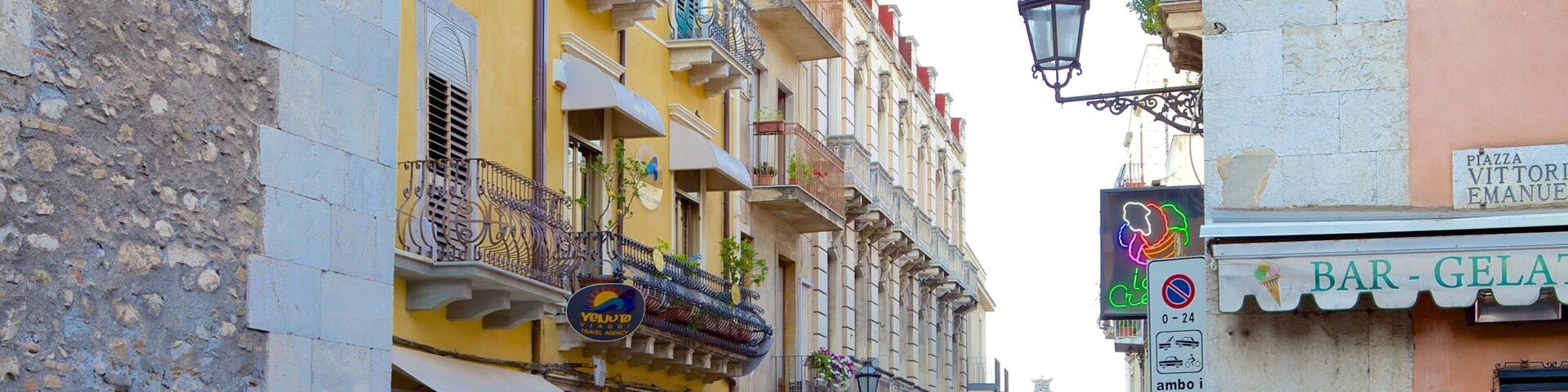 A bustling street with people walking, a gelato shop, and a bar.