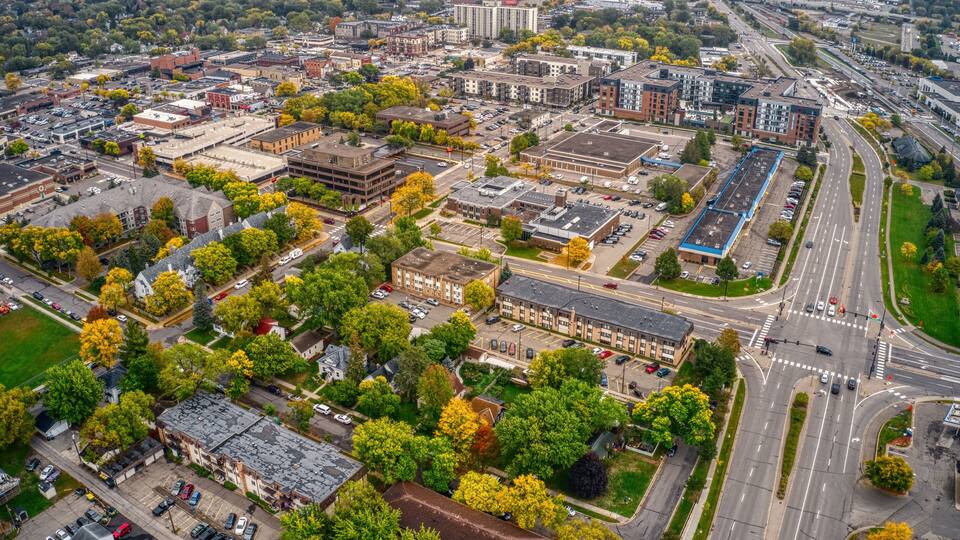 An aerial view of a city with a mix of modern and older buildings, roads, and surrounding greenery.