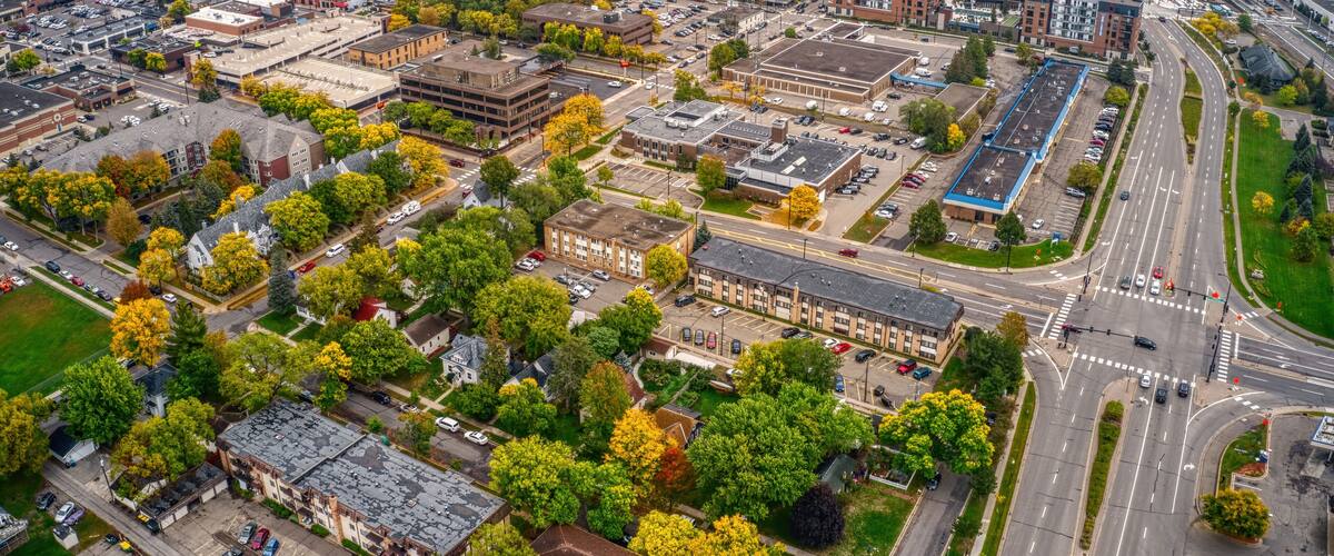 An aerial view of a city with a mix of modern and older buildings, roads, and surrounding greenery.