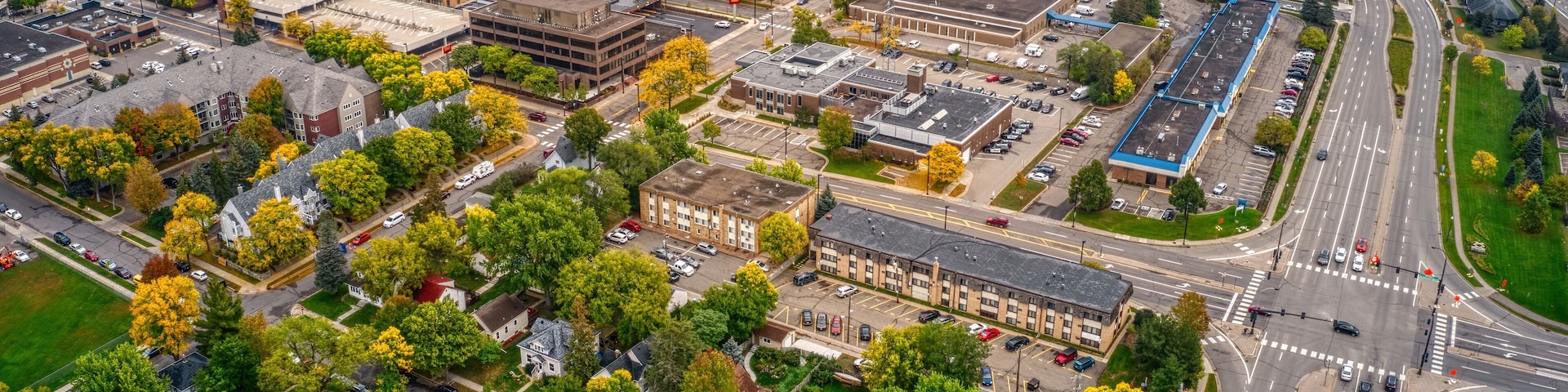 An aerial view of a city with a mix of modern and older buildings, roads, and surrounding greenery.