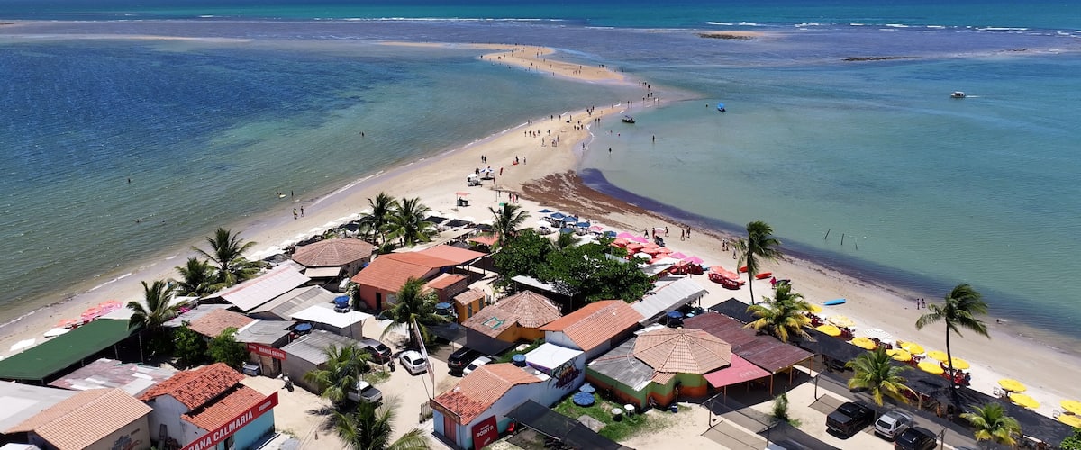 Una playa con aguas cristalinas, una orilla arenosa y una hilera de edificios frente al mar.