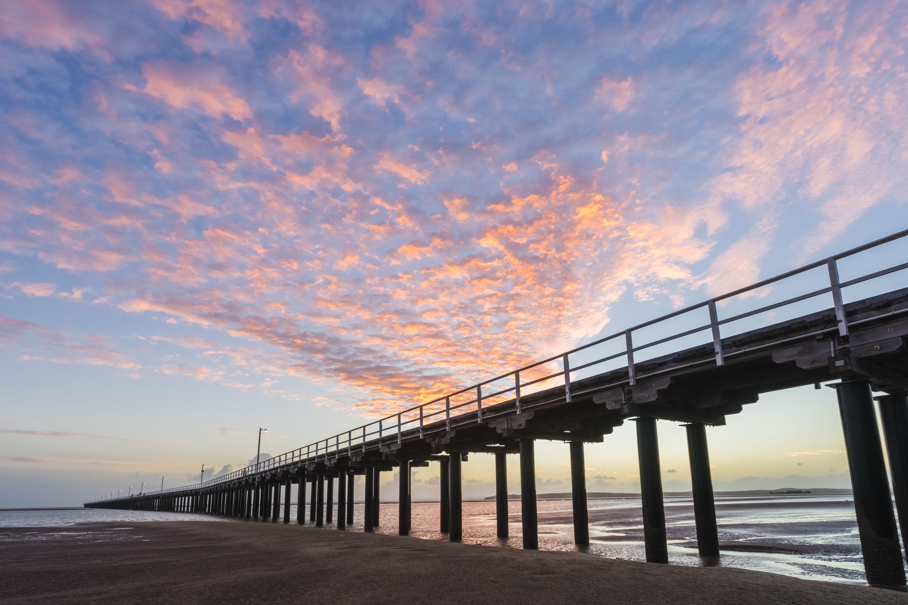 A pier extending into the sea with a sunset sky.