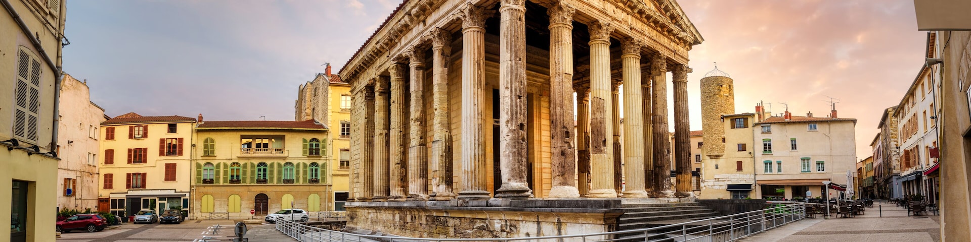 A classical building with columns, a fountain, and surrounding urban architecture.