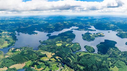 An aerial view of a large lake surrounded by lush green fields and forests.
