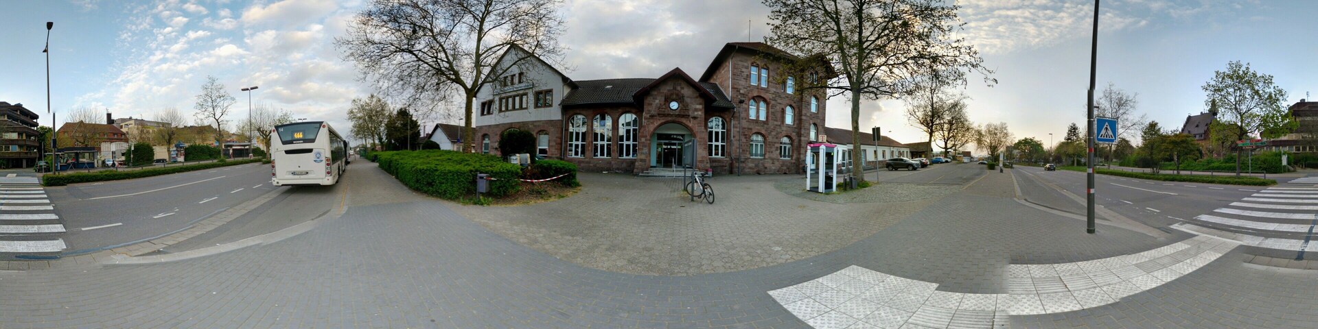 A roundabout with a large brick building, a bus, and a bicycle.