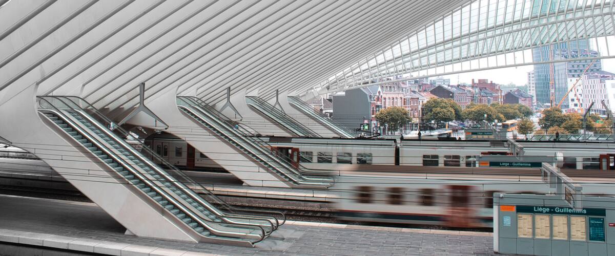 A modern train station with multiple escalators and a glass roof.