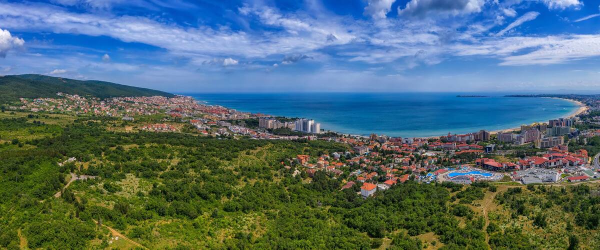 A coastal city with a beach, dense residential area, and a mountainous backdrop.