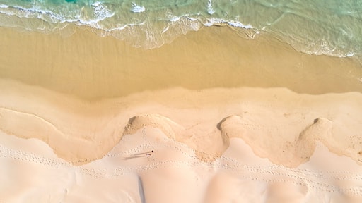 A sandy beach with clear turquoise water and gentle waves.