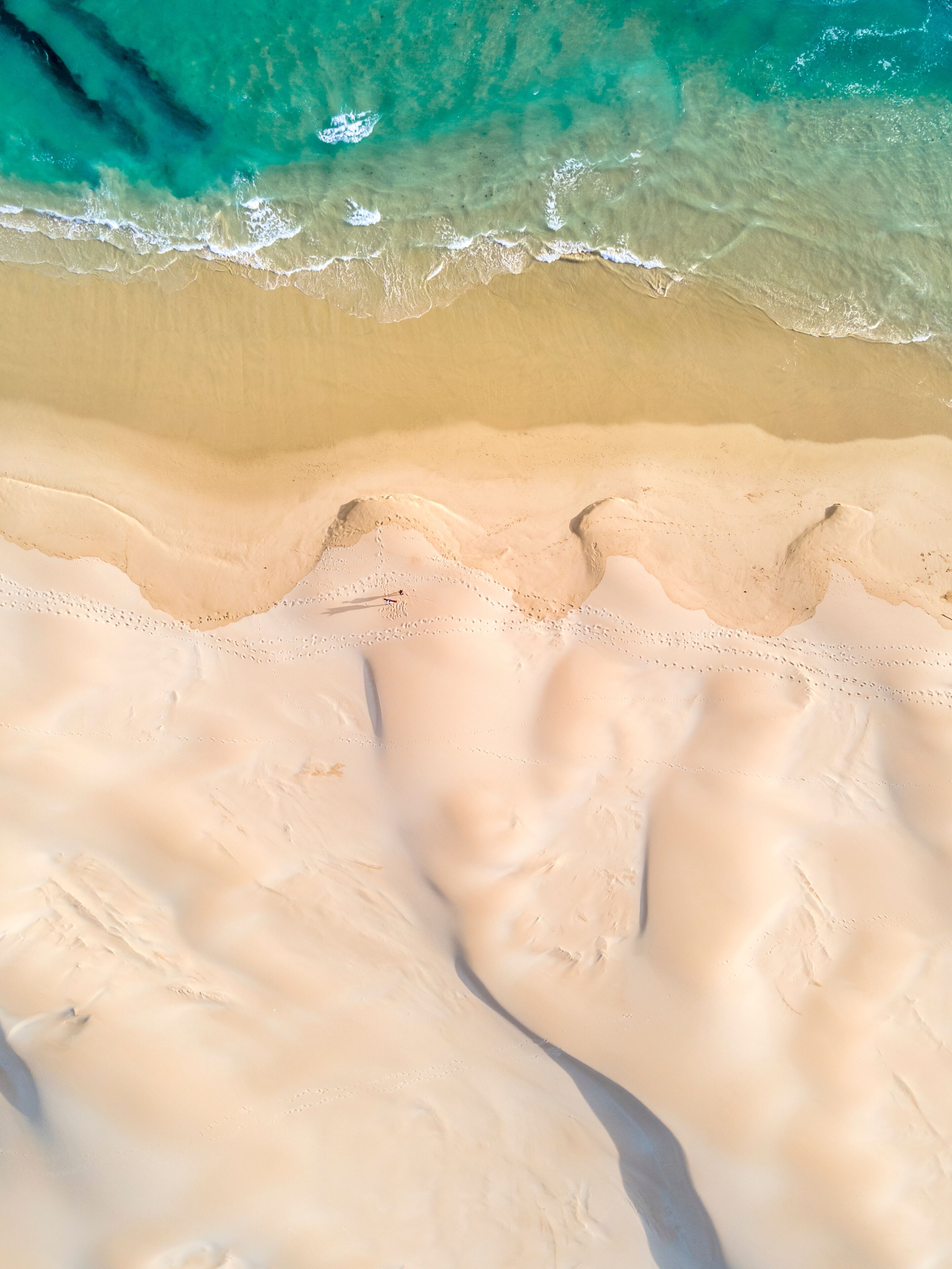 A sandy beach with clear turquoise water and gentle waves.