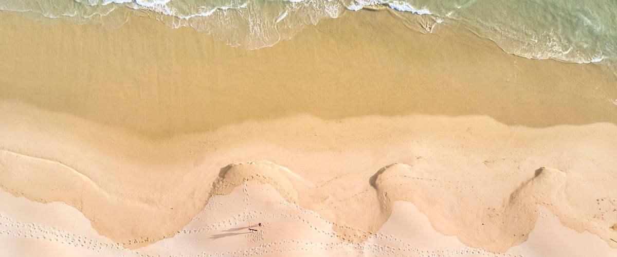 A sandy beach with clear turquoise water and gentle waves.