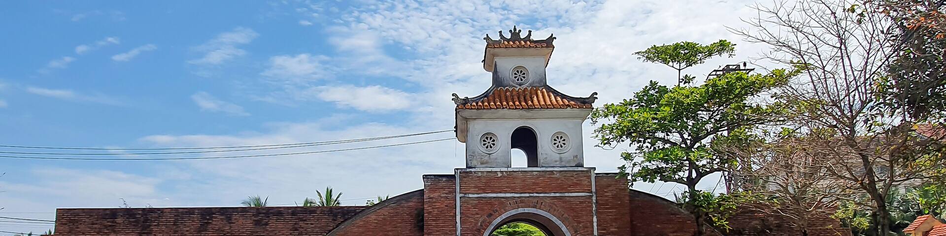 A brick gate with a tower and arched entrance.