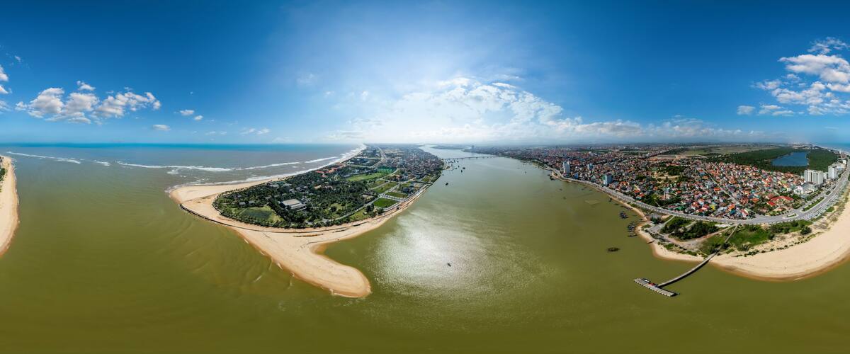 An aerial view of a coastal city with a river, a bridge, and a beach.