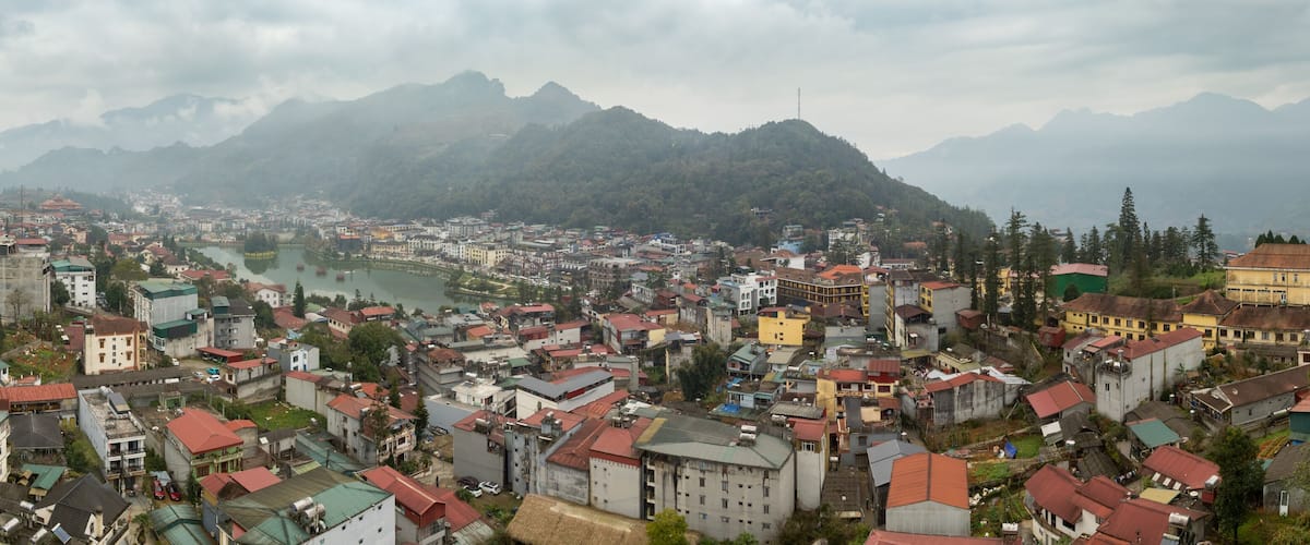 A mountainous town with a river, buildings, and greenery.