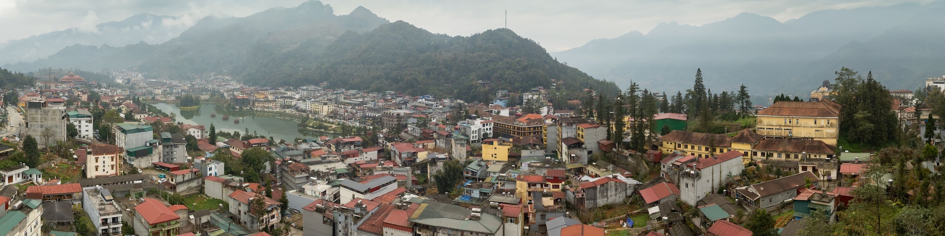 A mountainous town with a river, buildings, and greenery.