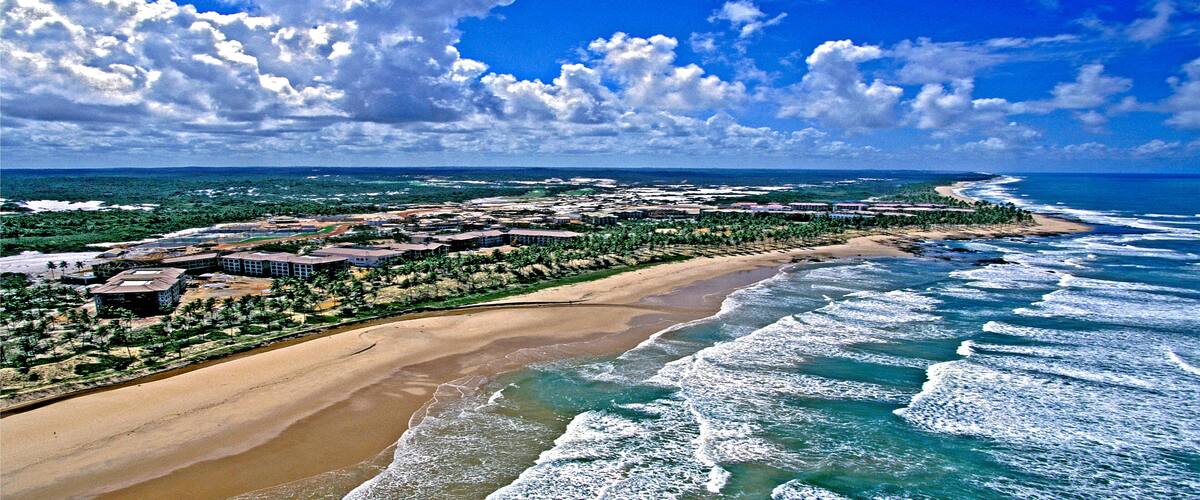 A coastal resort with a sandy beach, ocean waves, and a clear blue sky.
