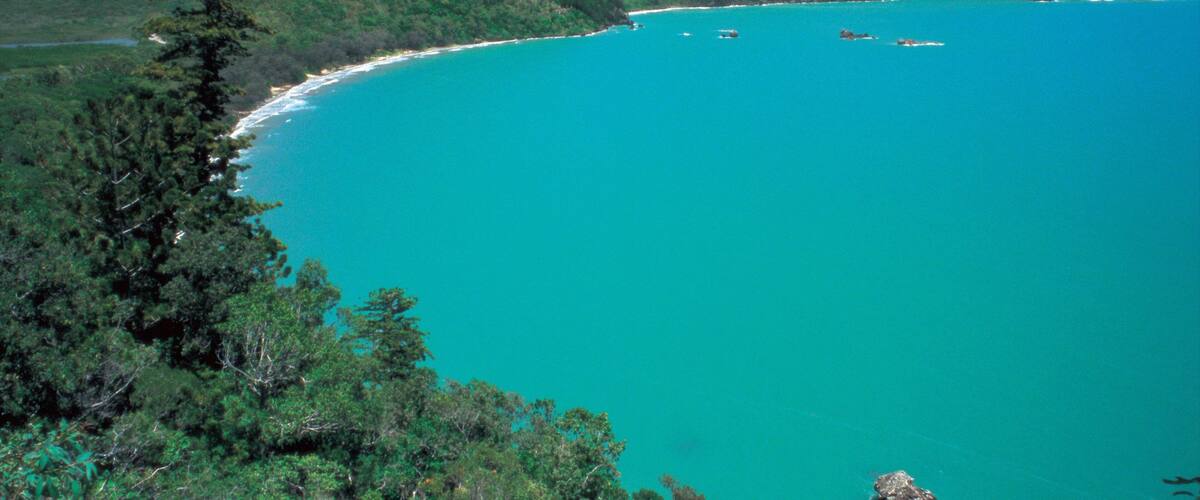 A turquoise coastal bay surrounded by green hills.