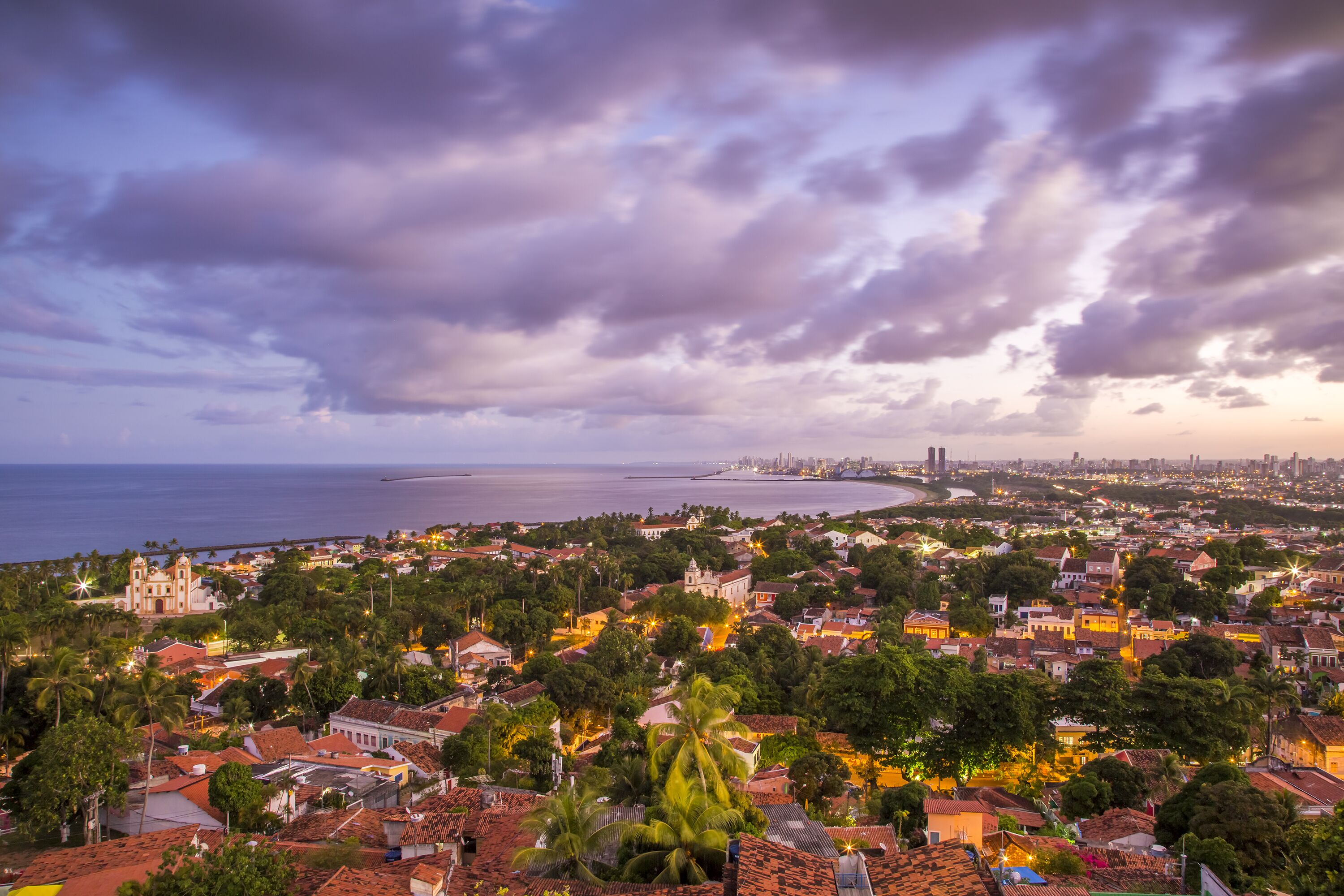 A coastal cityscape with a prominent church, dense residential areas, and a beach in the distance.