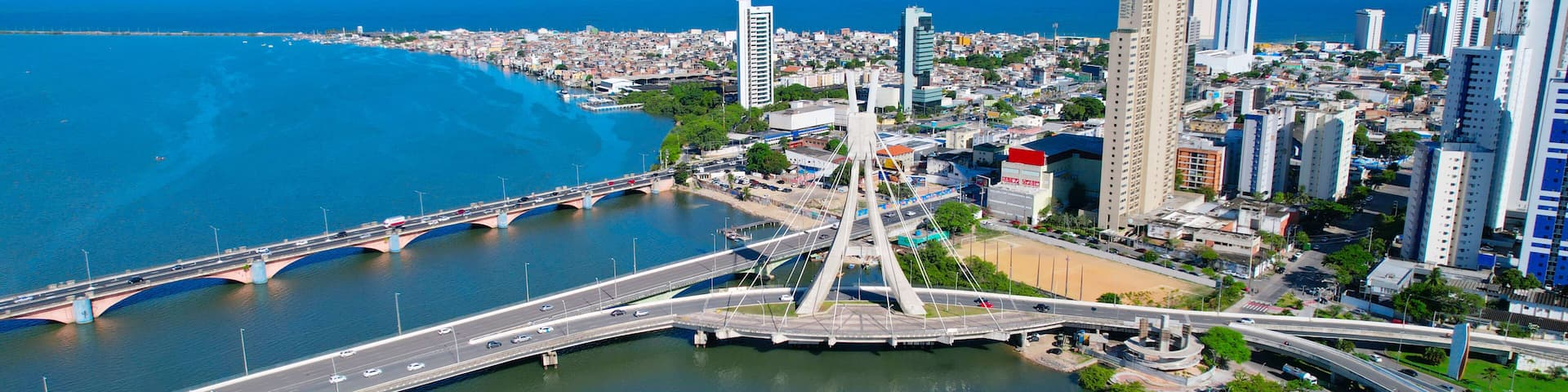 A cityscape with a prominent bridge, a river, and a coastal view.