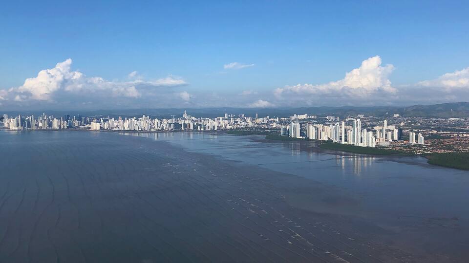 A coastal cityscape with high-rise buildings and a large body of water.