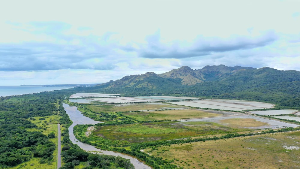 A river winding through a valley with mountains in the background and a road on the left.