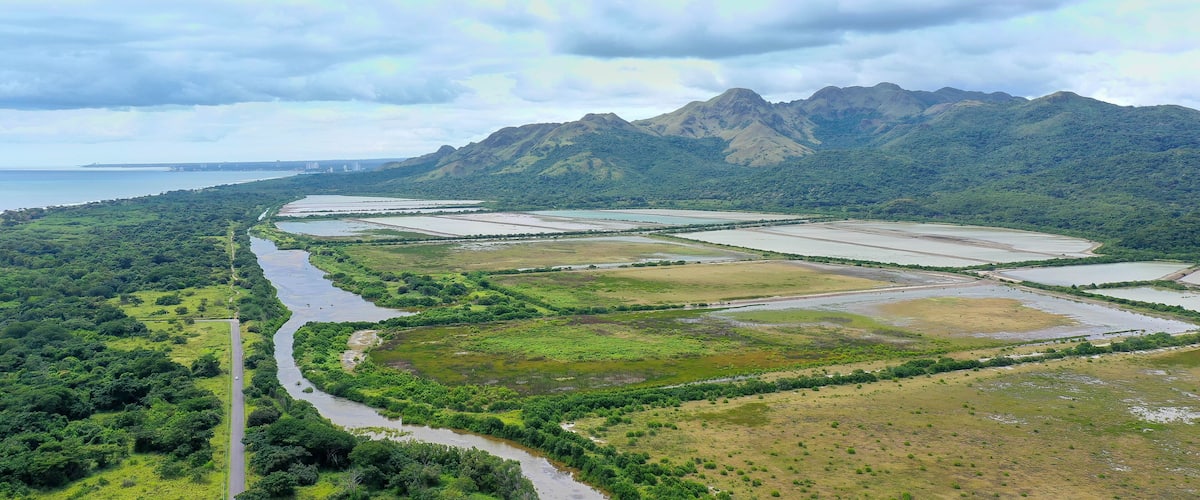 A river winding through a valley with mountains in the background and a road on the left.