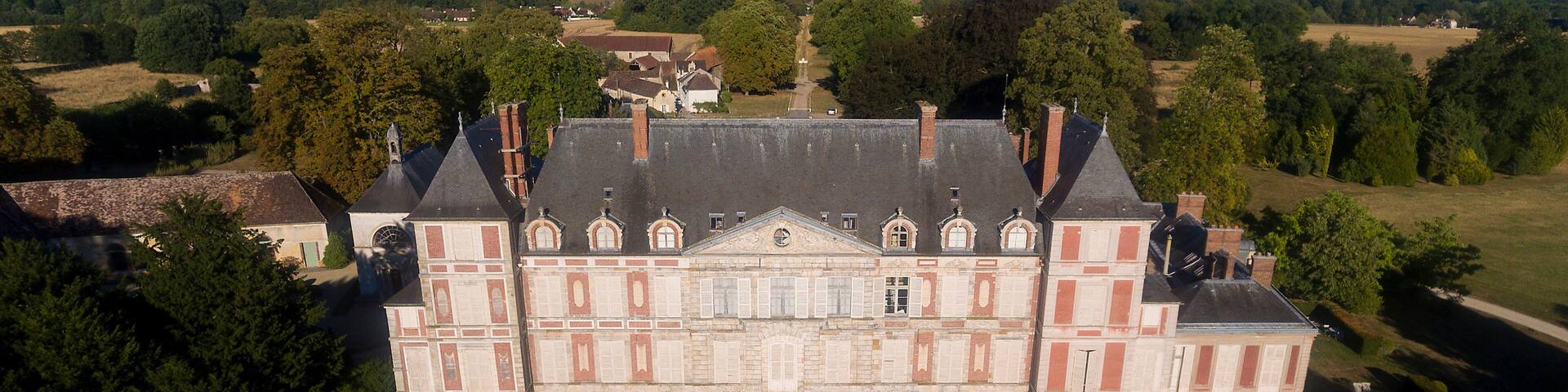 A large, historic building with a symmetrical facade, central entrance, and a formal garden.